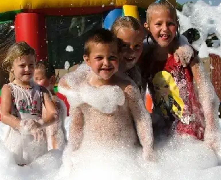 Delighted children covered in foam in the foam pit