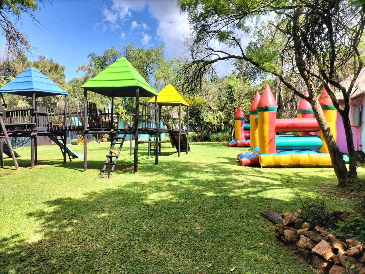 Jungle gyms and a jumping castle on the play area lawn
