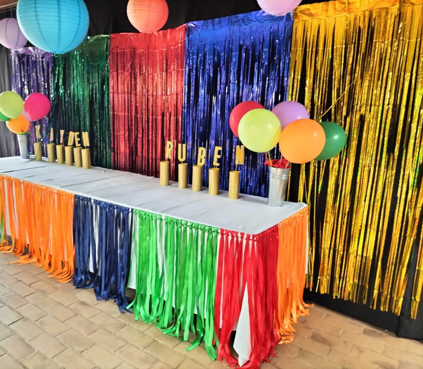Multi-coloured fringe curtain behind a long dessert table