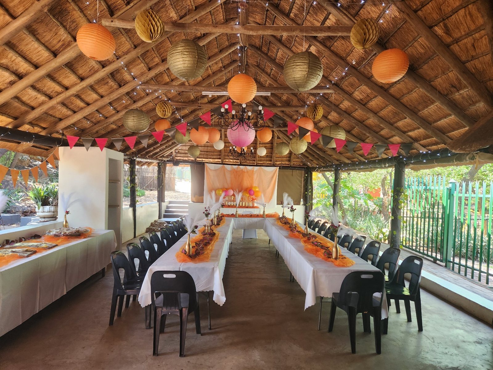 Long tables with orange runners and colourful lanterns