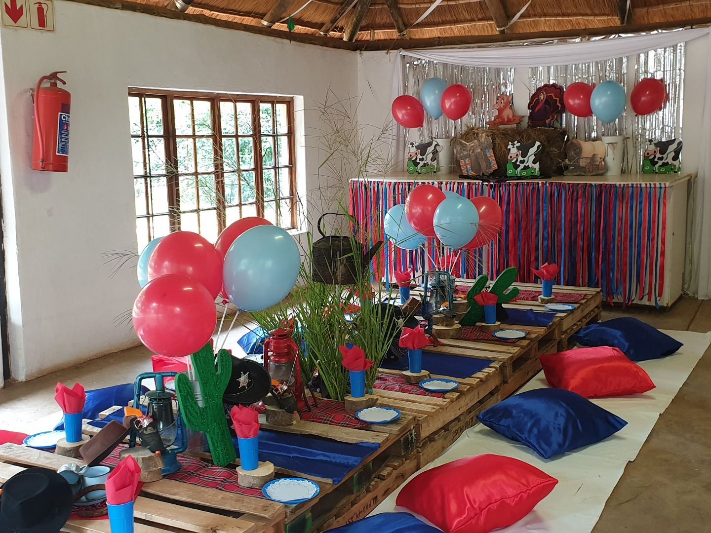 Red and blue themed party tables with cushions on the floor