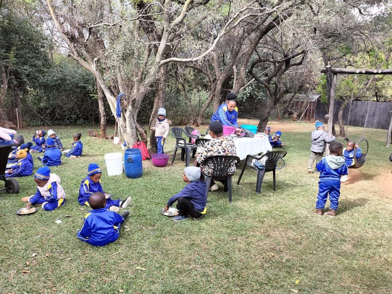 Learners sitting on the lawn having lunch under the trees