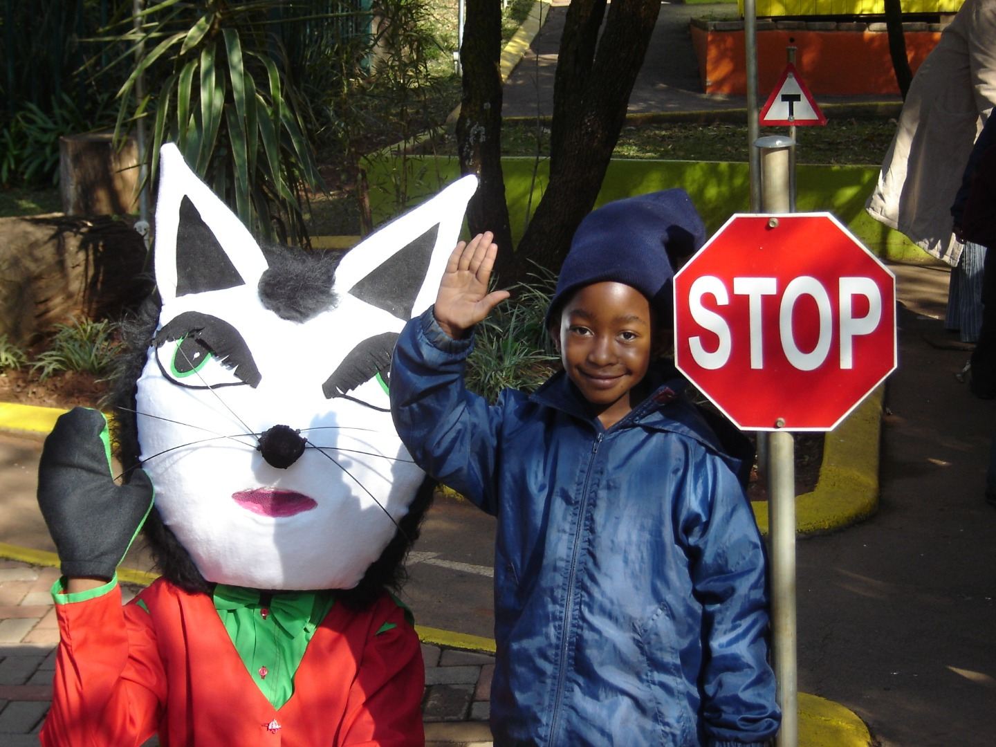 Danny Cat the mascot holding a stop sign with a young learner