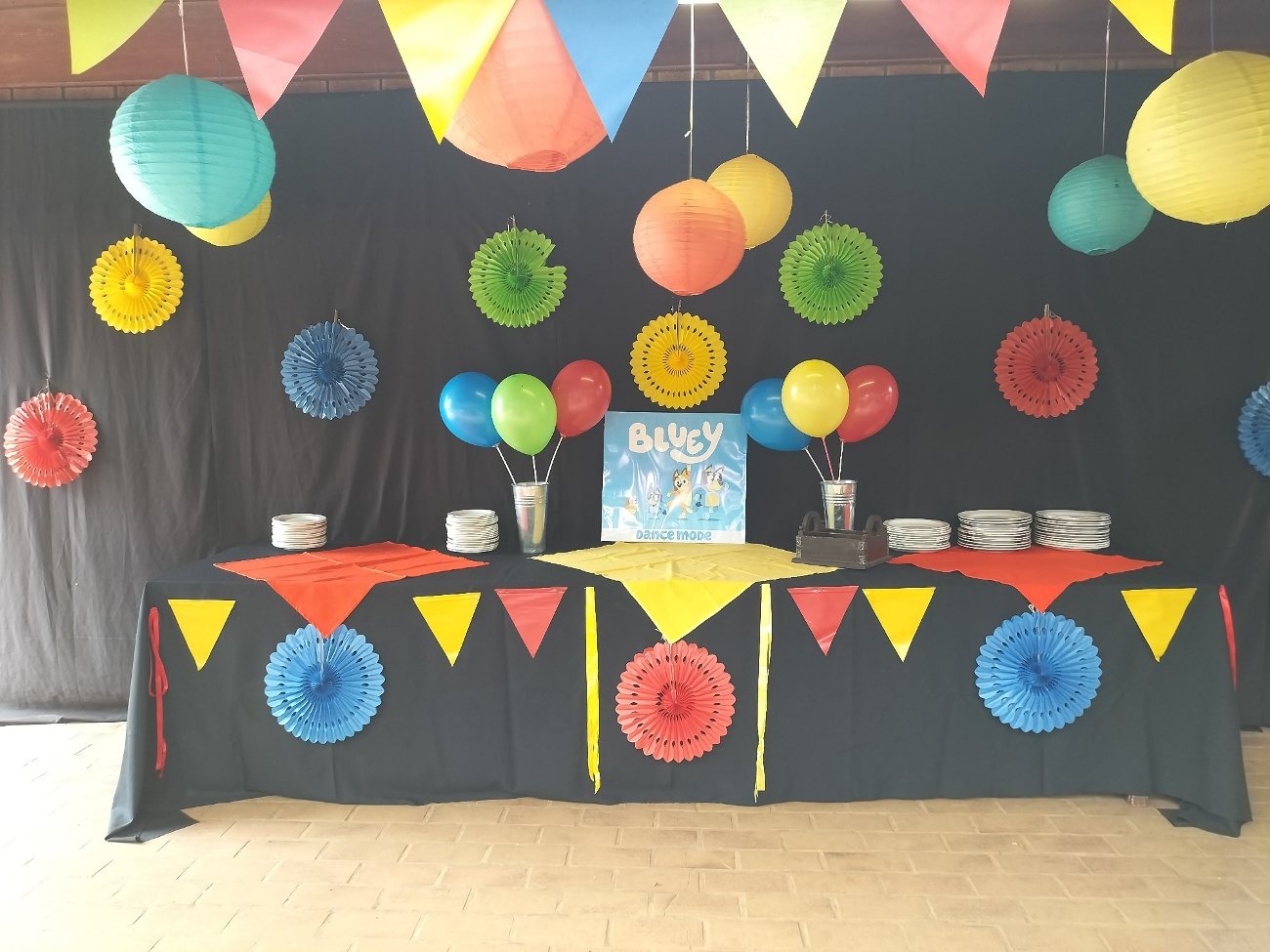 Bunting and paper fans above a dressed dessert table