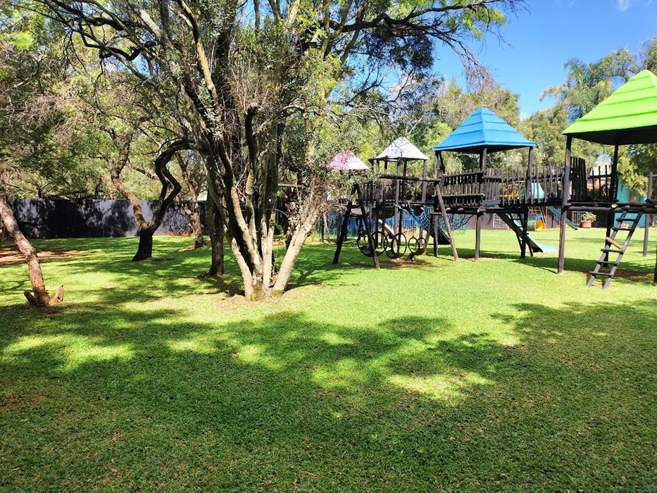 Sunlit lawns of The Garden venue with jungle gyms among the trees