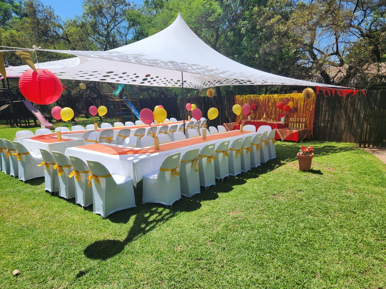 Long banquet tables under the stretch tent on the garden lawn